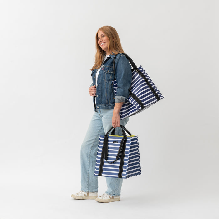 Woman holding two striped bags against a white background