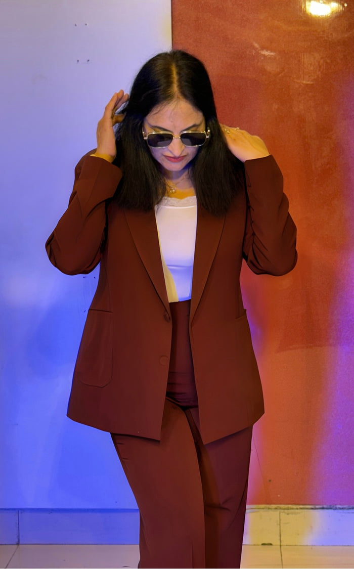 Person wearing a brown suit and sunglasses against a colorful wall.