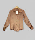 Brown satin shirt on a hanger against a colorful background